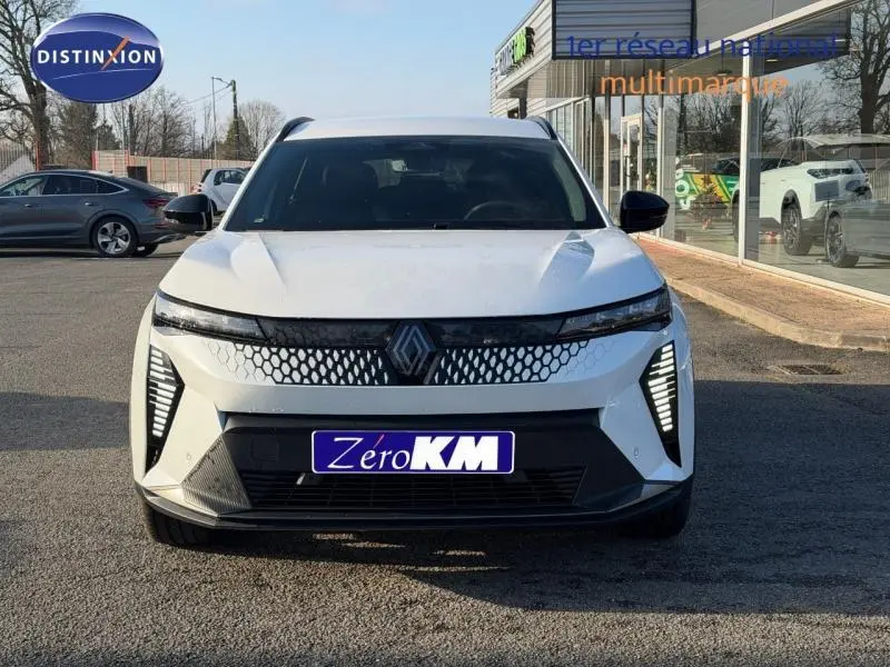 Vue frontale d'un Renault Scénic E-Tech électrique blanc avec calandre à motif hexagonal et feux LED verticaux.