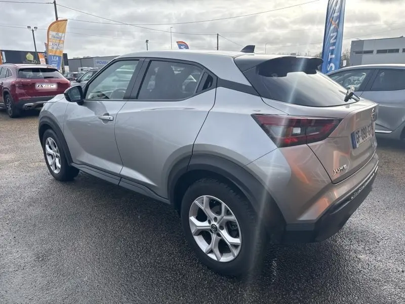 Vue 3/4 arrière droite d'un Nissan Juke gris perle métallisé avec jantes alliage et toit noir, stationné en extérieur.