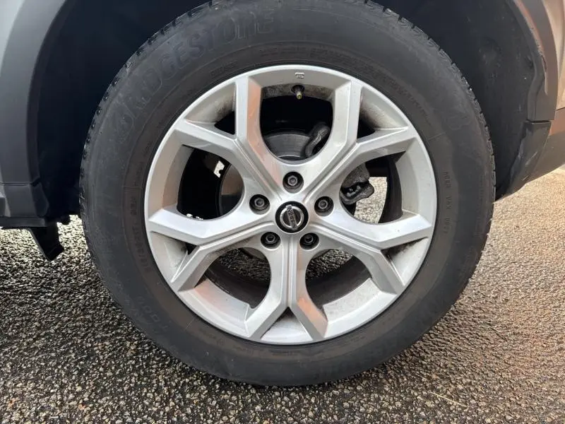 Gros plan sur la jante alliage argentée du côté gauche d'un Nissan Juke gris perle métallisé, avec pneu Bridgestone.
