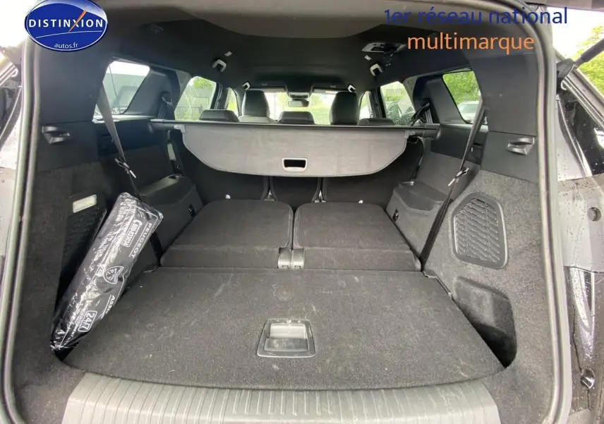 Vue arrière du coffre noir du Peugeot 5008 Hybrid 145 allure e-dcs6 avec banquette rabattue et cache-bagages déployé.