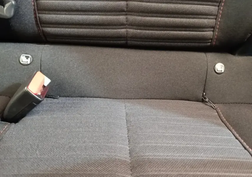 Gros plan sur la banquette arrière noire du Peugeot E-2008 électrique, montrant les fixations Isofix et la ceinture de sécurité.