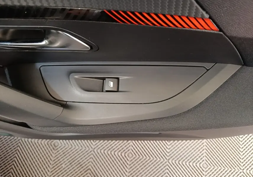 Détail de la porte intérieure côté conducteur du Peugeot E-2008 électrique gris clair, avec bouton de commande de vitre.