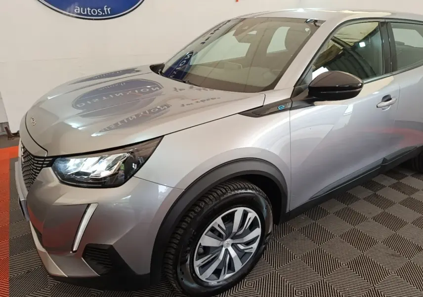 Vue 3/4 avant droit d’un Peugeot E-2008 électrique gris clair avec phares LED et jantes alliage distinctives.
