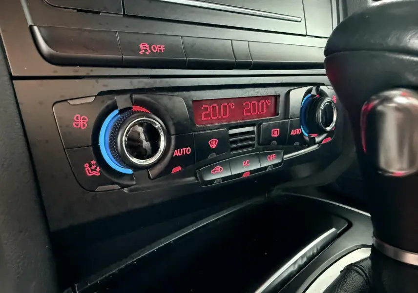 Gros plan sur la console centrale de l'Audi A5 gris, montrant la climatisation automatique réglée à 20°C.