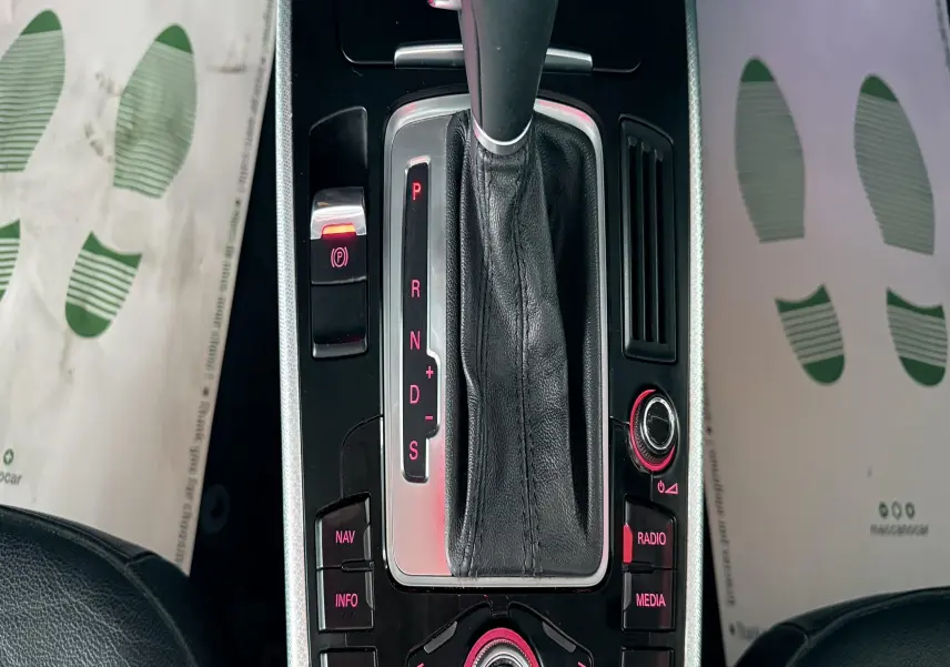 Vue rapprochée de la console centrale noire et argentée de l'Audi A5 2011 avec levier de vitesses automatique et commandes rétroéclairées rouges.