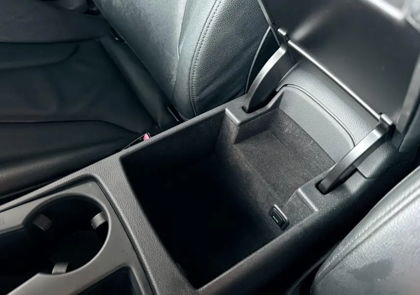 Gros plan sur le rangement central ouvert en cuir noir de l'Audi A5 Sportback 2011, avec prise AUX visible.