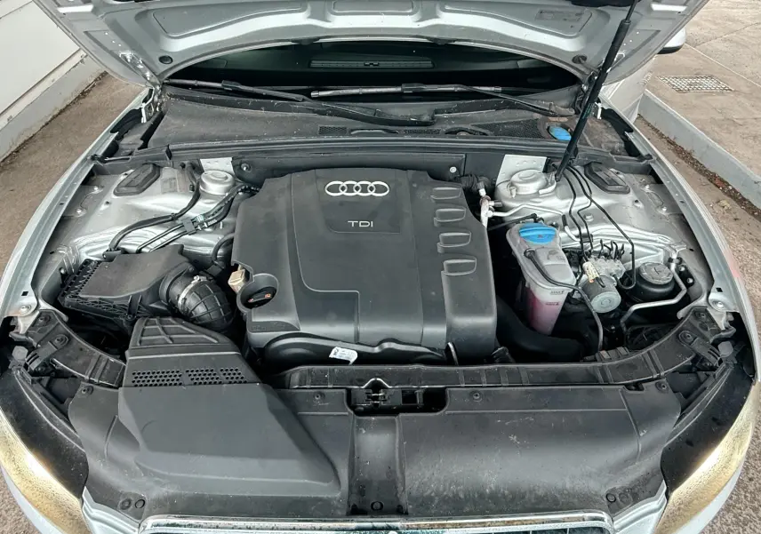 Vue plongeante sur le moteur TDI d'une Audi A5 gris avec capot ouvert montrant les composants sous le capot.