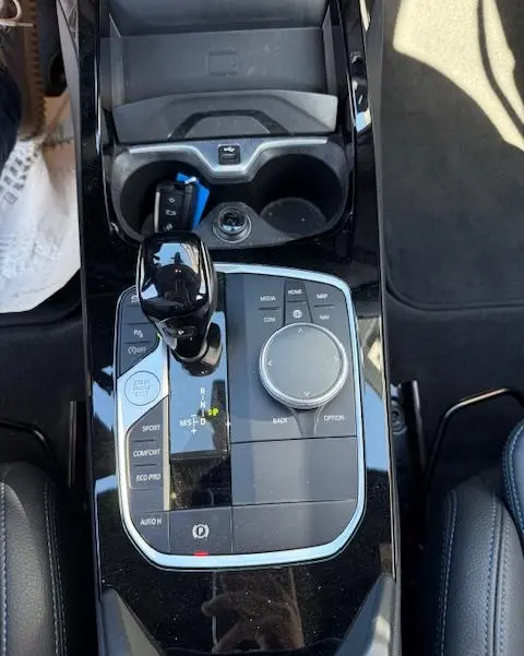 Vue plongeante sur la console centrale noire brillante de la BMW Série 1 118d Edition Sport avec levier de vitesses et molette de commande.
