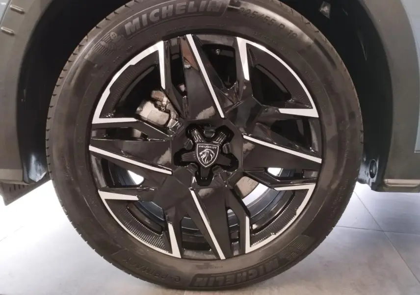 Gros plan sur la jante alliage noire diamantée 19'' avec logo Peugeot au centre, montée sur un pneu Michelin.