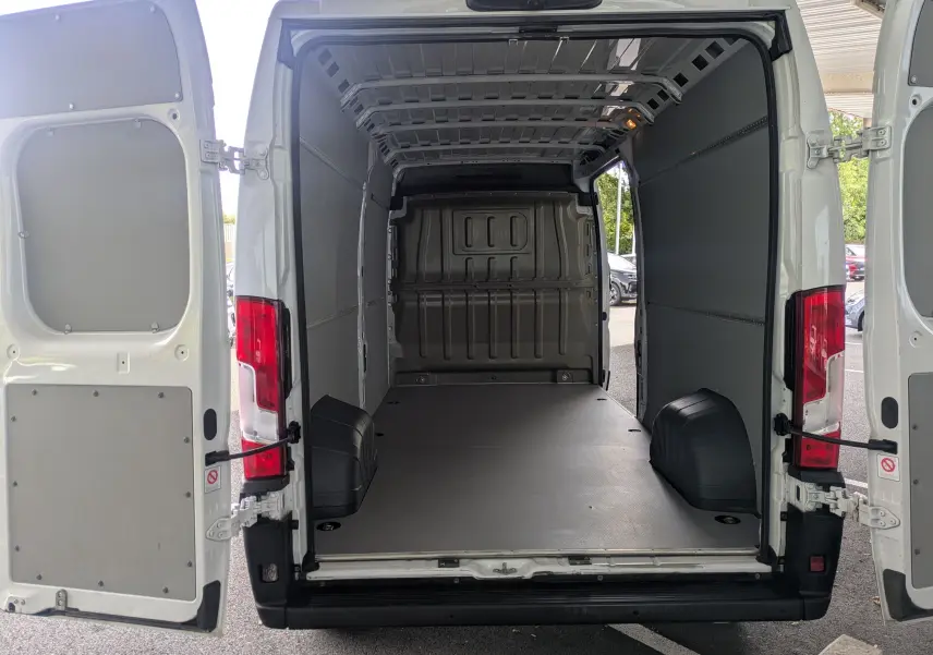 Vue arrière du fourgon blanc FIAT Ducato L3H2 2025 avec portes ouvertes montrant l'espace de chargement vide et spacieux.