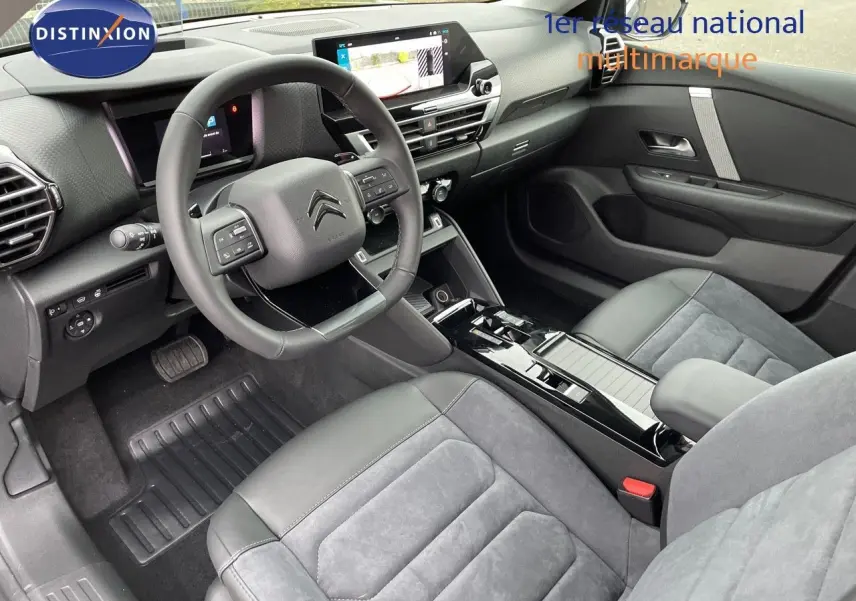 Intérieur avant de la Citroën C4 2024, vue côté conducteur, sièges gris cuir et alcantara, tableau de bord moderne avec écran tactile.