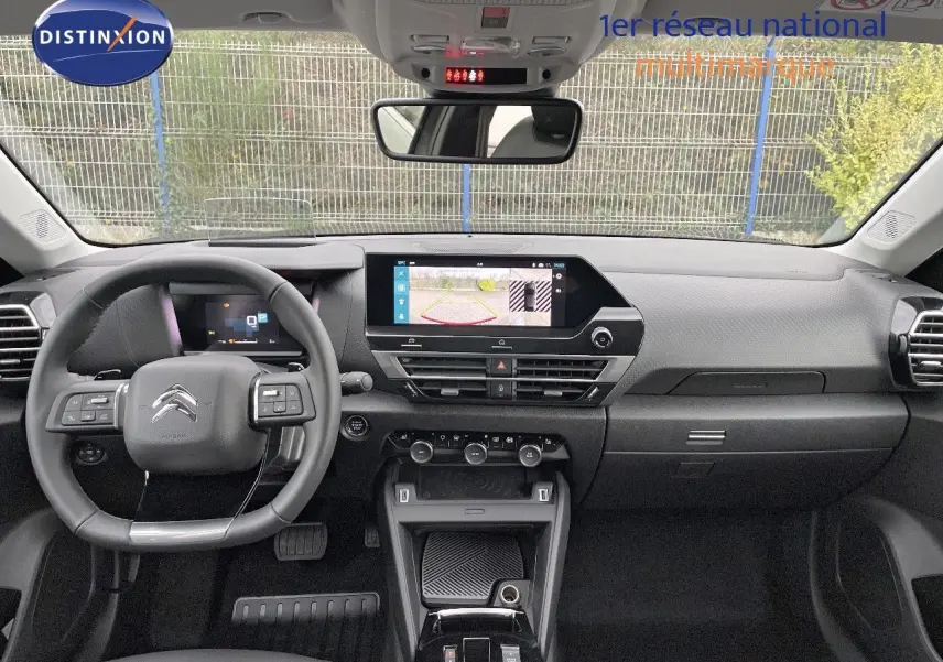 Intérieur de la Citroën C4 2024 en vue frontale, tableau de bord moderne avec écran tactile et volant multifonction noir.