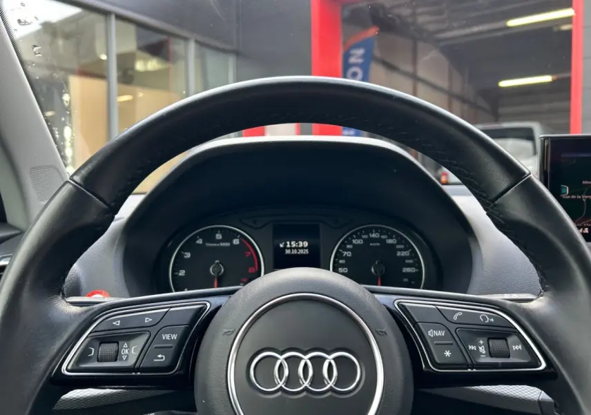 Vue centrée du volant cuir Audi Q2 noir 2023 avec combiné d'instruments et commandes multifonctions visibles.