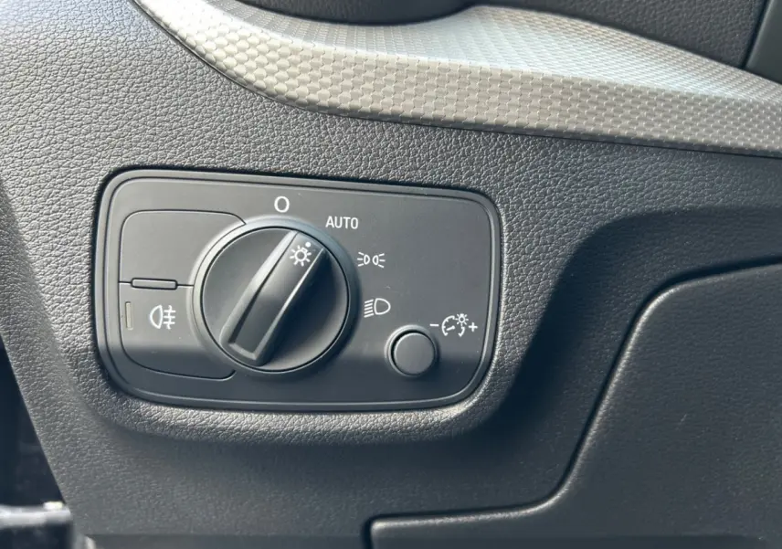 Gros plan sur le bouton de commande des phares noir dans l'habitacle de l'Audi Q2 35 TFSI S Line 2023.