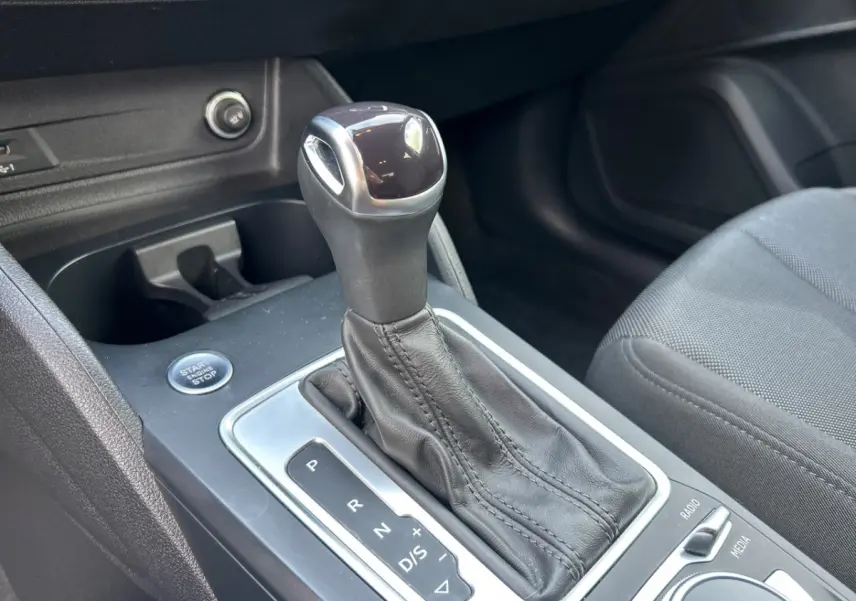 Gros plan sur la commande de boîte automatique noire et le bouton start/stop dans l'habitacle d'un Audi Q2 noir.