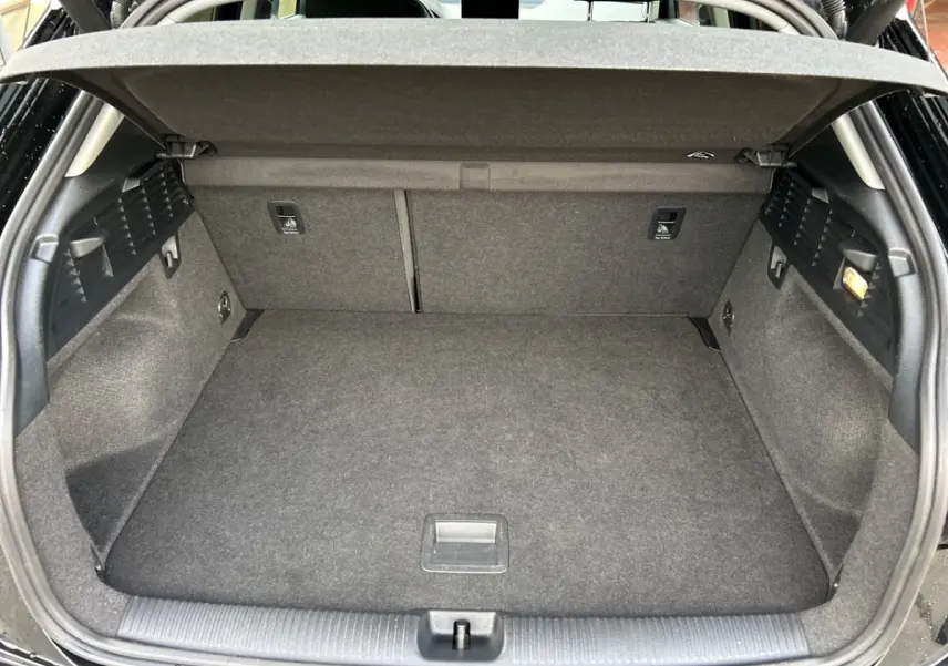 Coffre ouvert vu de l'arrière d'un Audi Q2 noir 2023, montrant un espace de chargement propre et bien fini.