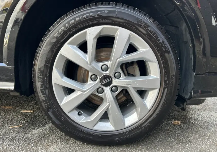 Gros plan sur la roue avant droite argentée d'un Audi Q2 noir 2023 avec jante en alliage et pneu Triangle.