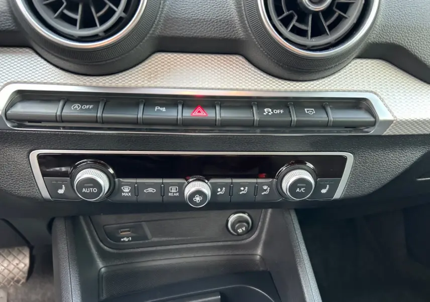 Détail du tableau de bord noir de l'Audi Q2 35 TFSI 2023 avec commandes climatisation et ventilation.