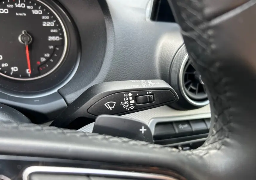 Gros plan sur la commande des essuie-glaces et le volant cuir noir de l'Audi Q2 35 TFSI 2023 côté gauche.