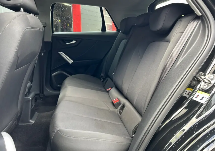 Vue côté droit sur la banquette arrière noire de l'Audi Q2 35 TFSI 150 S Line 2023 avec portes ouvertes.
