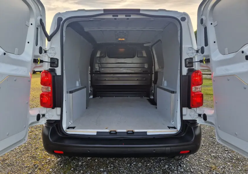 Vue arrière du fourgon FIAT Scudo blanc 2024 avec portes ouvertes montrant l'espace de chargement vide et protégé.