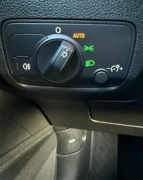 Gros plan sur le bouton de commande des phares avec réglage automatique, intérieur noir de l'Audi Q2 35 TFSI 2023.