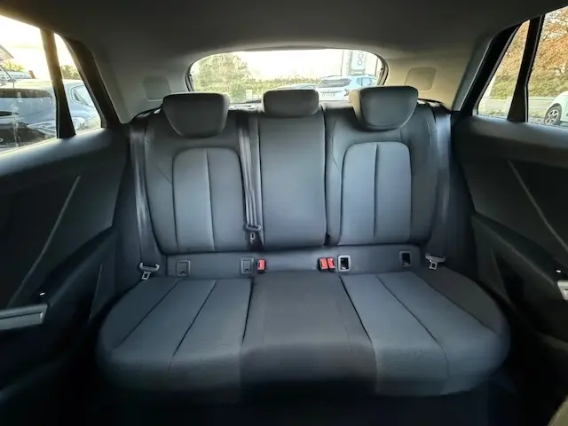 Vue arrière de la banquette arrière noire de l'Audi Q2 35 TFSI 150 S Tronic S Line 2023 avec appuie-têtes et ceintures visibles.