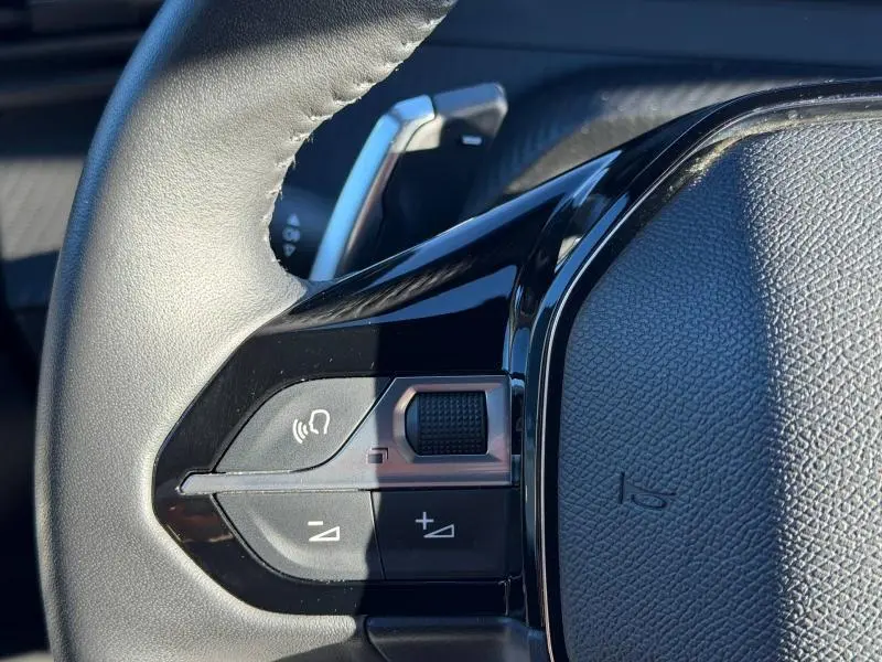 Gros plan sur les commandes gauche du volant gris du Peugeot 2008 2024, avec molette et boutons multifonctions.