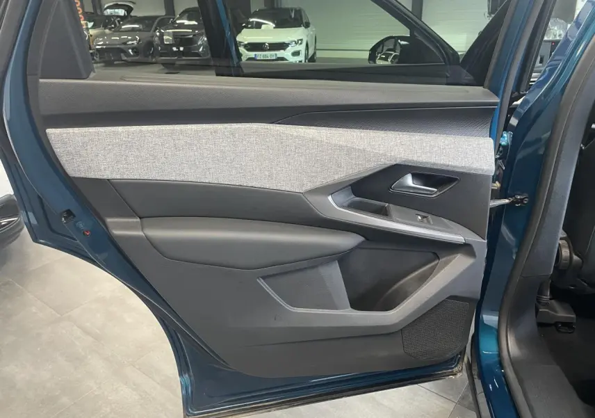 Vue intérieure de la porte arrière gauche bleu Obsession du Peugeot 5008 2025 avec habillage tissu gris et noir.