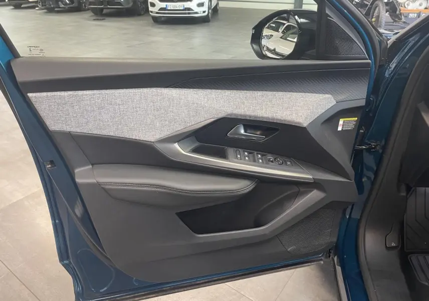 Vue intérieure de la porte avant gauche du Peugeot 5008 Bleu Obsession avec habillage tissu et commandes électriques.