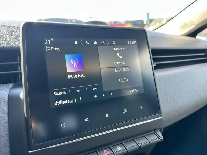 Écran tactile central affichant la radio et téléphone, intérieur gris de la Renault Clio 2025 côté passager.