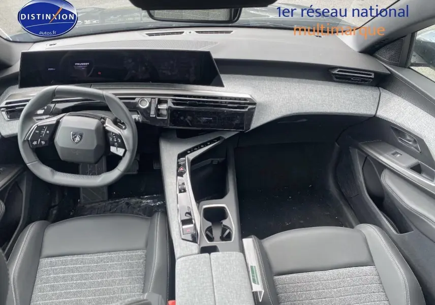 Vue intérieure avant du Peugeot 5008 Hybrid 145 Allure 2025, soulignant le volant cuir multifonction et la console centrale grise.