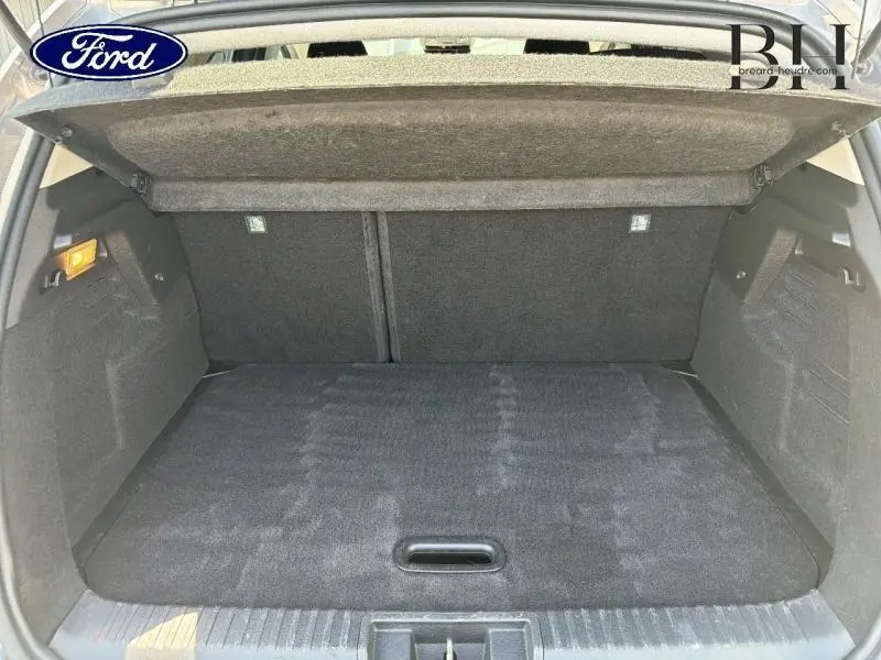 Coffre ouvert vu de l'arrière d'un Renault Captur gris Cassiopée métallisé, espace de chargement vide et tapis noir.
