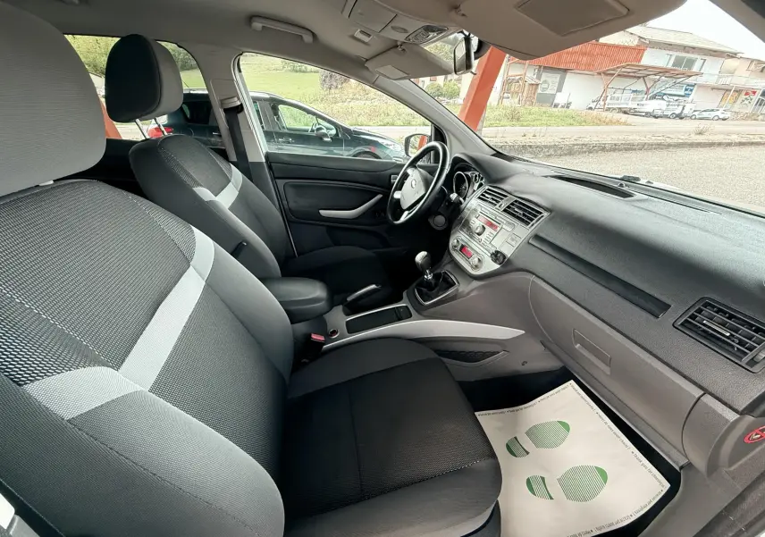 Intérieur avant droit du Ford Kuga 2012 avec sièges tissu gris et tableau de bord noir simple et fonctionnel.