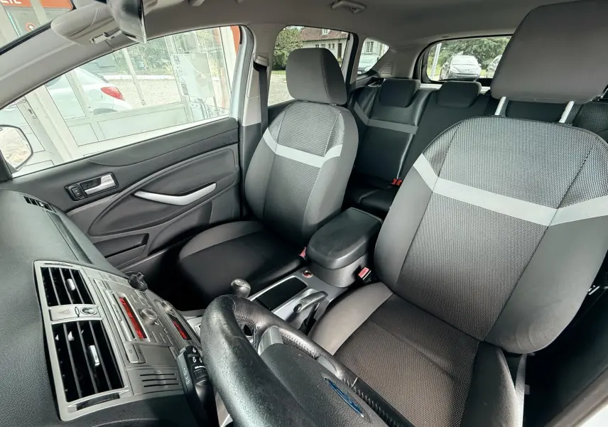 Intérieur du Ford Kuga 2012 montrant les sièges avant en tissu gris et noir avec tableau de bord et volant visibles.