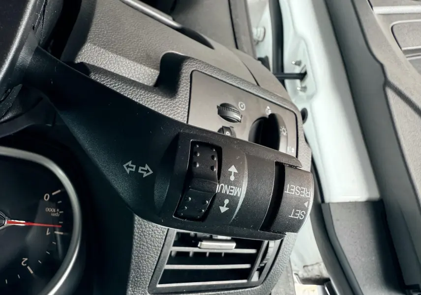 Gros plan sur la commande de clignotants et menu du tableau de bord du Ford Kuga blanc, côté gauche intérieur.