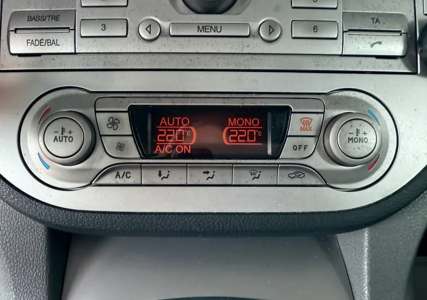 Vue rapprochée de la console centrale du Ford Kuga 2012 montrant la climatisation automatique à 22°C et les commandes radio.