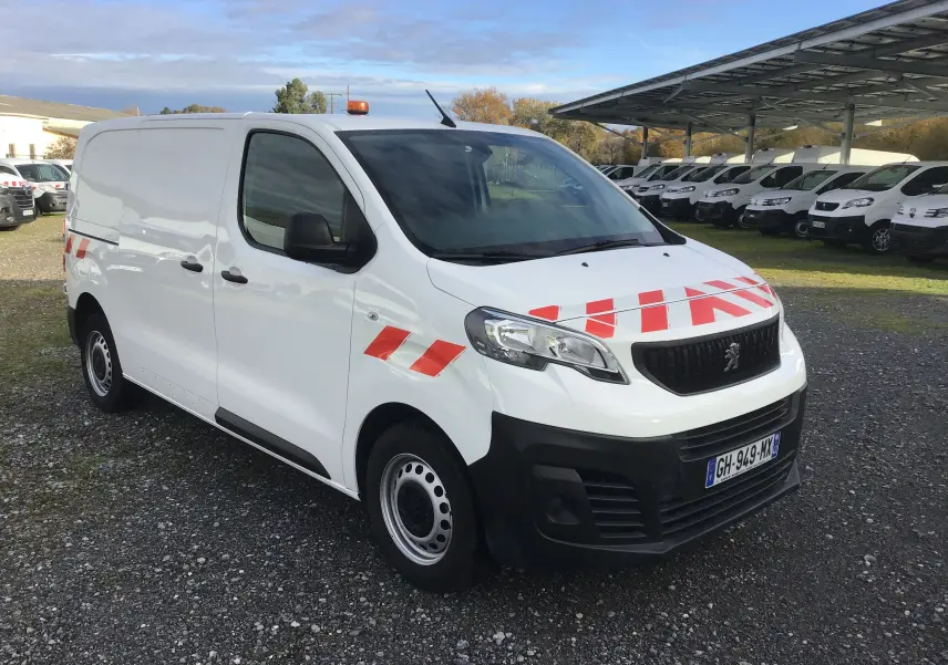 Vue 3/4 avant droit d'un Peugeot Expert Fourgon blanc 2022 avec bandes rouges et gyrophare orange sur le toit.