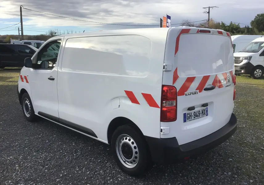 Vue arrière du Peugeot Expert Fourgon blanc 2022 avec portes ouvertes montrant l'intérieur équipé de rangements gris.