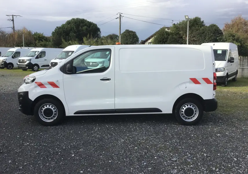 Intérieur du Peugeot Expert Fourgon blanc 2022 vu côté conducteur, montrant sièges et tableau de bord noir.
