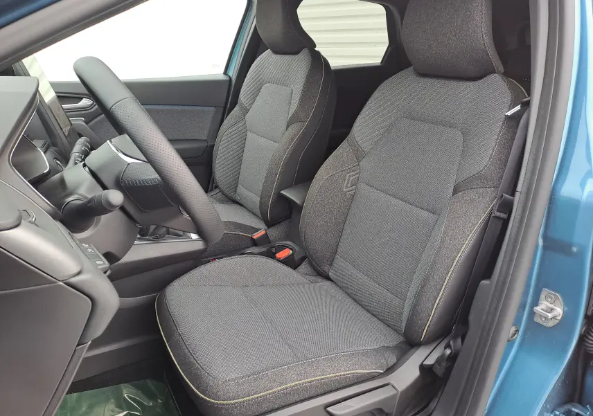 Vue intérieure côté conducteur de la Renault Symbioz bleu mercure, sièges tissu gris avec surpiqûres jaunes et volant perforé.
