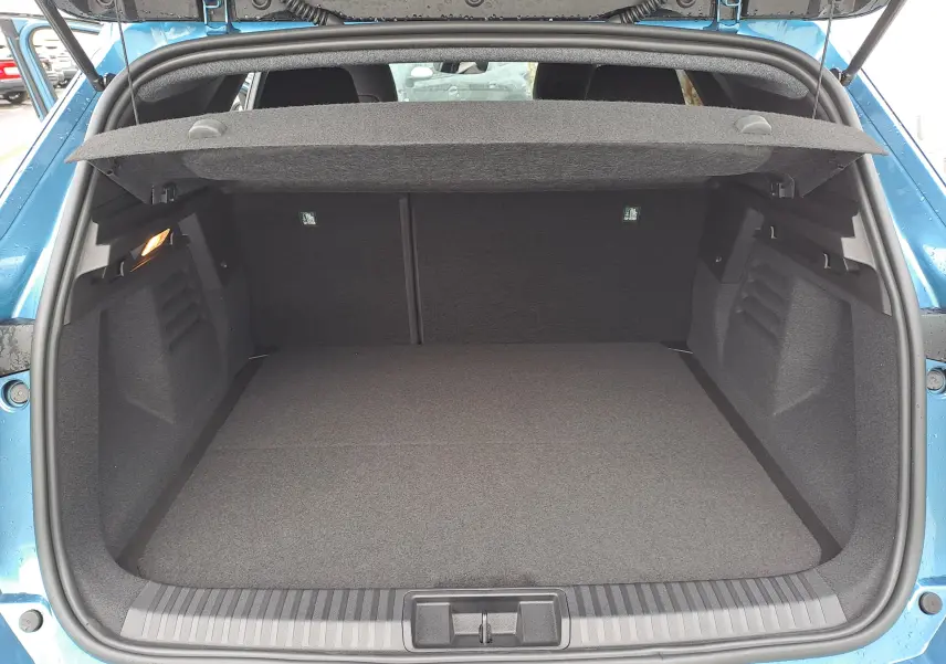 Coffre ouvert vu de l'arrière d'une Renault Symbioz bleu mercure, montrant un espace de chargement spacieux et propre.