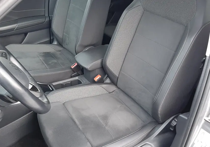 Vue intérieure côté conducteur du Volkswagen T-Roc gris pyrite 2023 avec sièges noirs en tissu et alcantara.
