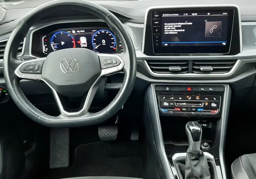 Vue intérieure du tableau de bord et volant Volkswagen T-Roc 2023, avec écran tactile et levier de vitesse automatique.
