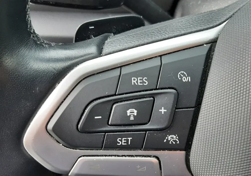 Gros plan sur les commandes au volant du Volkswagen T-Roc 2023, boutons de régulateur de vitesse et assistance au maintien de voie.