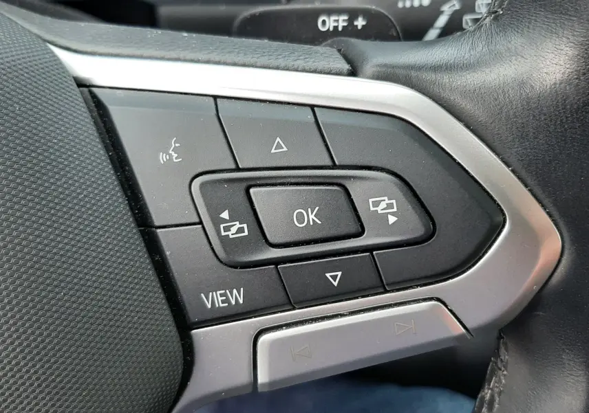 Gros plan sur les commandes multifonctions du volant en cuir noir du Volkswagen T-Roc gris pyrite.