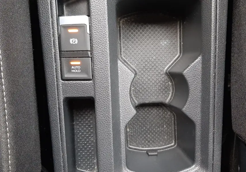 Gros plan sur la console centrale noire du Volkswagen T-Roc 2023 avec boutons frein à main électrique et auto hold.