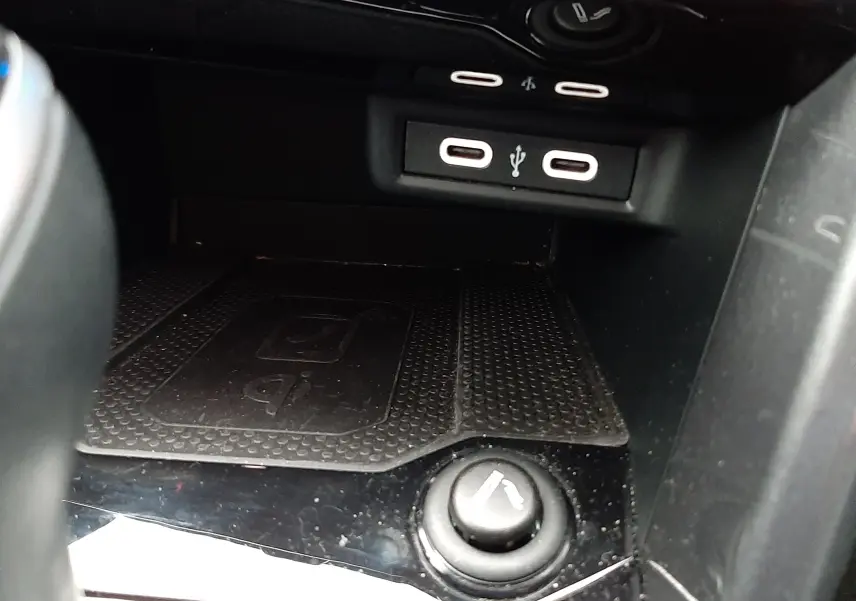 Vue rapprochée de la console centrale du Volkswagen T-Roc gris, montrant les ports USB et un allume-cigare.