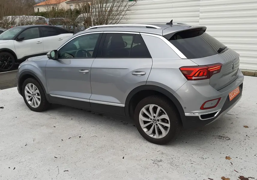 Volkswagen T-Roc gris pyrite vu en 3/4 arrière droit, avec vitres arrière surteintées et jantes alliage.