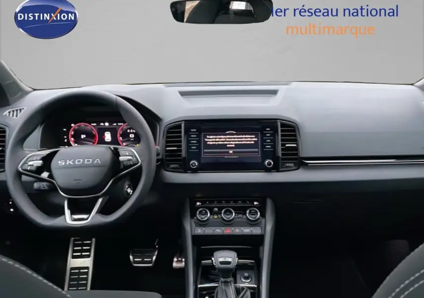 Tableau de bord intérieur noir du Skoda Karoq 2025, vue frontale centrée sur volant et écran tactile.